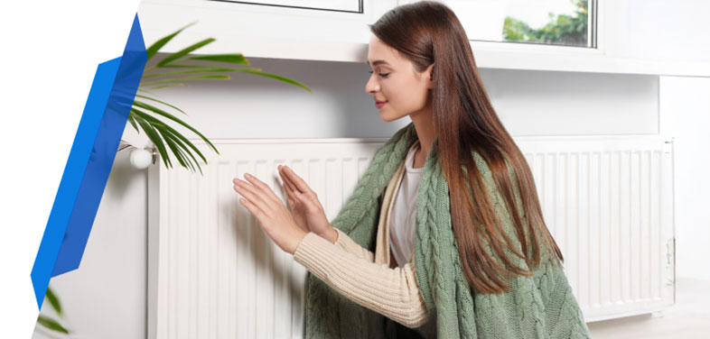 Woman warming hands by radiator, representing central heating cover and emergency boiler protection