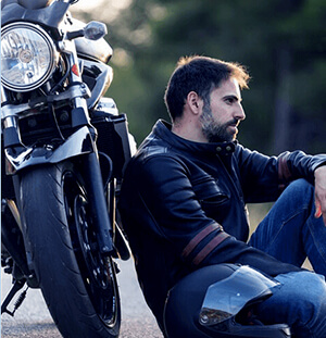 Image of a motorbike with a person sitting beside it on the road