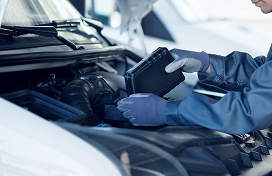 Mechanic inspecting the engine of a vehicle with the bonnet open