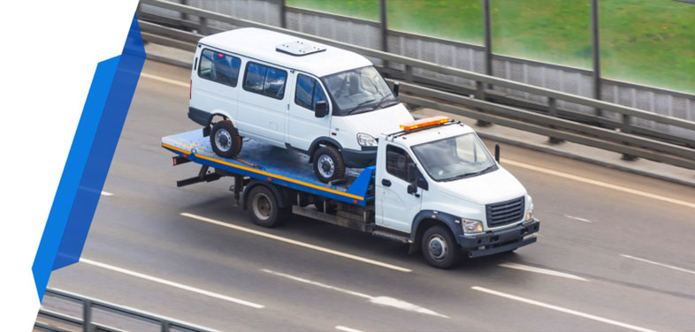 A white taxi minibus being carried by a white recovery truck, covered by a Smart Cover minibus breakdown insurance policy