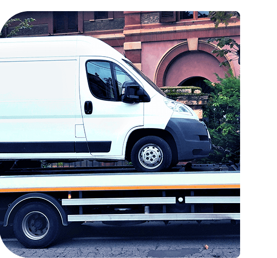 Image of a white taxi mini bus loaded onto a recovery truck.